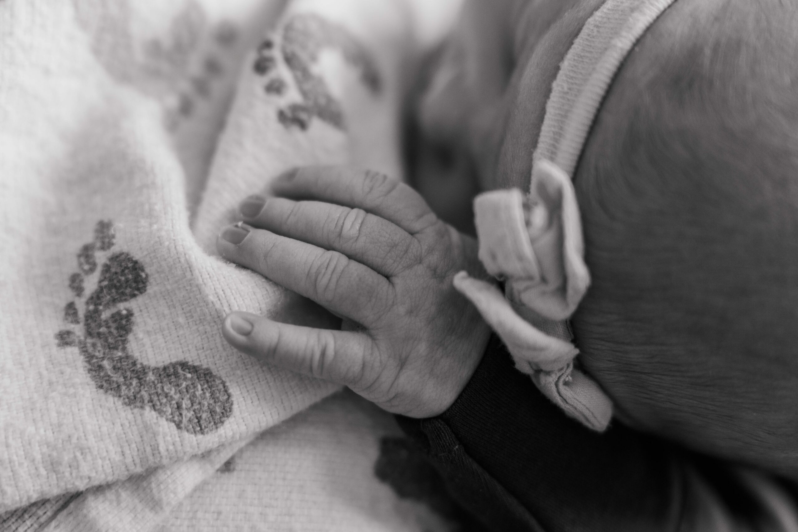 Newborn's hand lays on hospital blanket