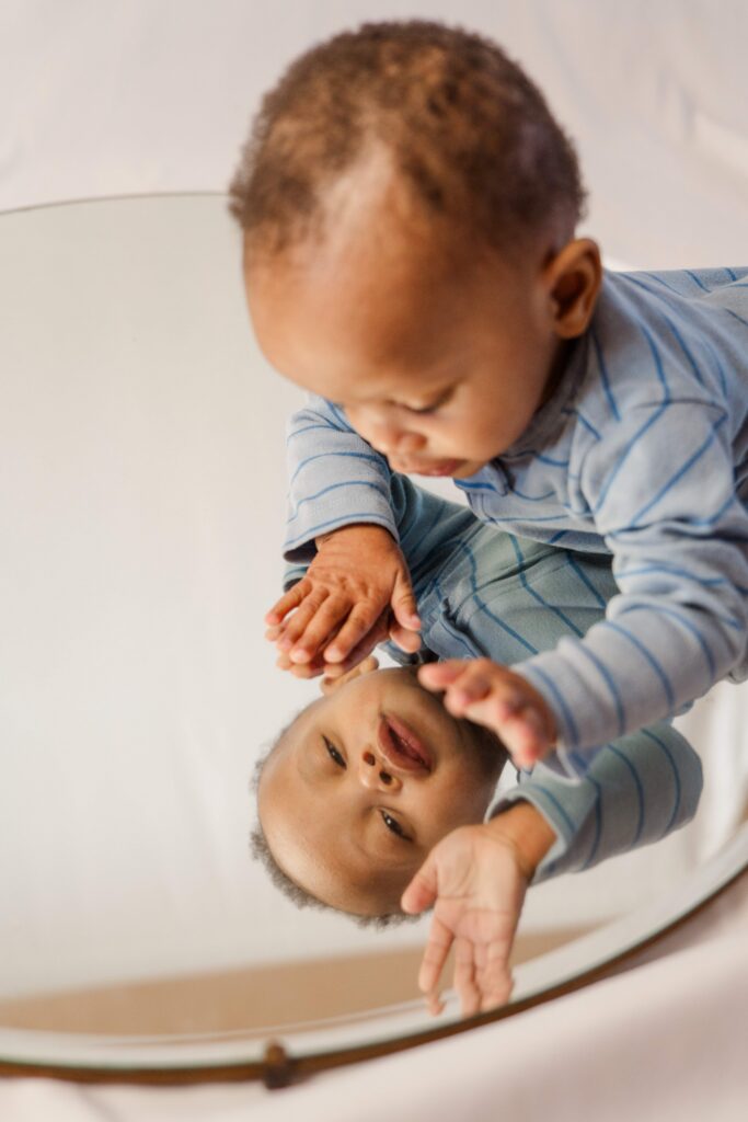 Baby waves at himself in the mirror