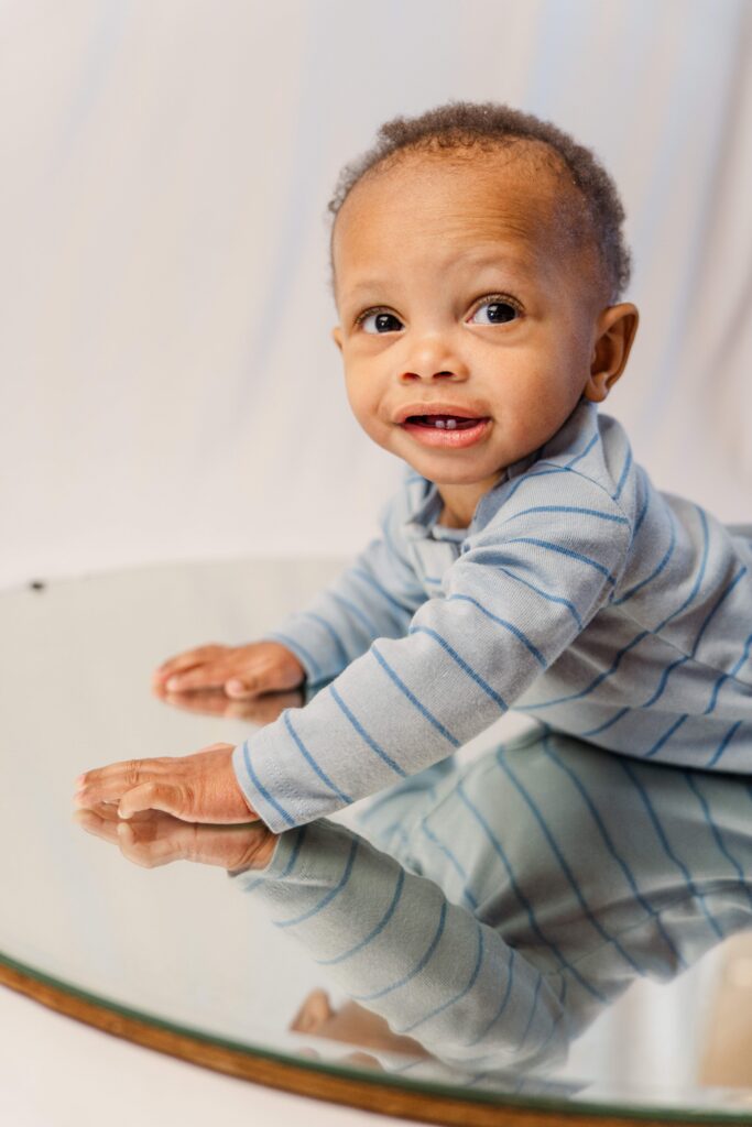 At baby photos Pueblo West, baby smiles at the camera while lifting himself off the ground