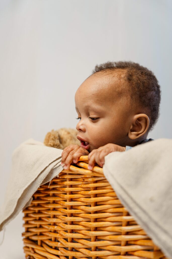 Baby grabs the edge of basket and looks over the side.