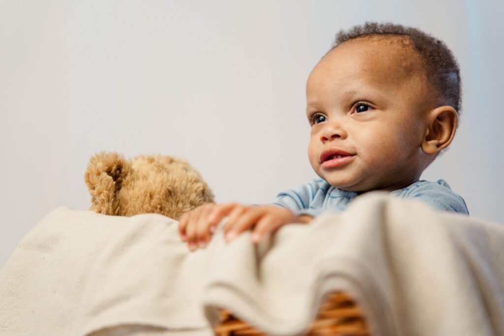 Baby hold the side of a big basket and looks off to the side