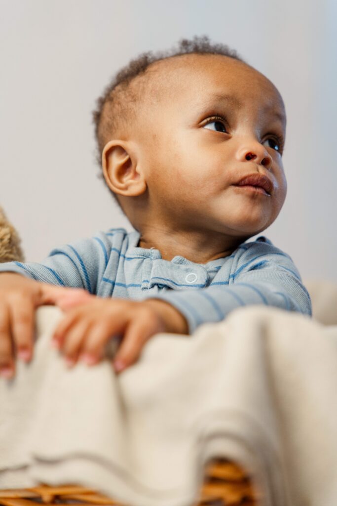 Baby grabs the edge of basket and looks off to the side