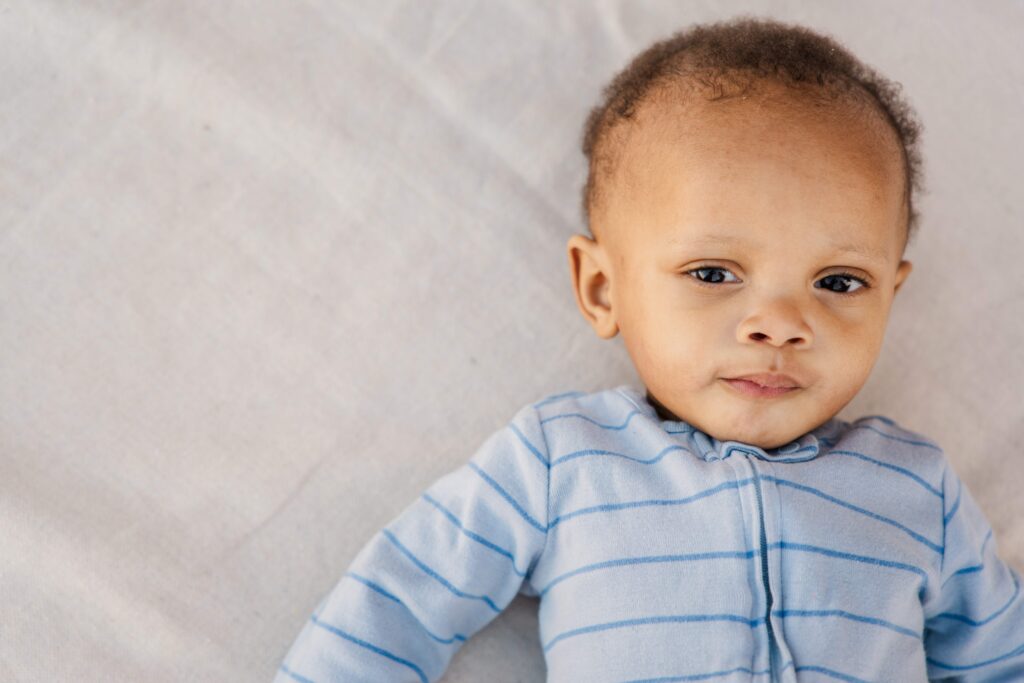 Baby is laying on the ground and has a serious face